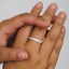 Hand wearing a silver ring on a plain background
