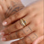 Hand wearing a gold ring with a blue stone on a white background