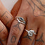 Close-up of a hand wearing two silver rings with blue stones on a light background