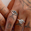 Close-up of a hand wearing two silver rings with blue stones on a light background